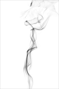 Grayish black smoke vapors wafting upward on a white background