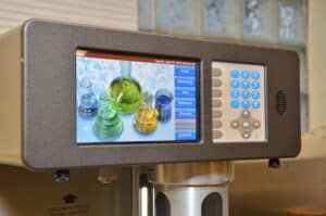 A picture of laboratory equipment showing the start screen, featuring a picture of a bunch of beakers filled with colorful liquids.