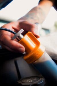 Close up of the top of a quick-draw pump with used engine oil flowing through the tubing