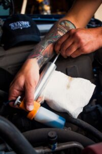 Image of a hand holding an oil sample bottle with used oil in it
