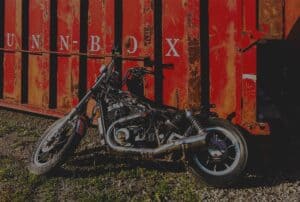 Motorcycle leaning against a dumpster