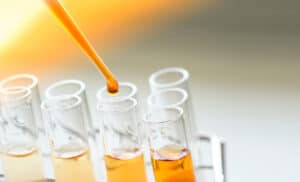 An eye dropper dropping oil into a row of test tubes.