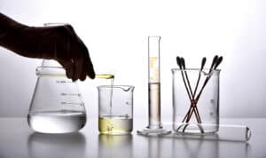 Glassware with silhouetted hand pouring oil into a beaker