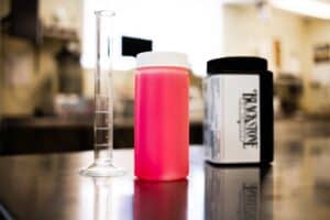 Sample bottle containing red coolant next to a graduated cylinder and an oil sampling kit