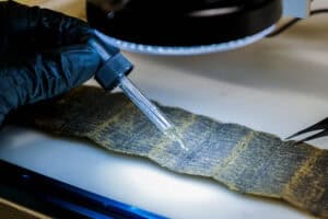 a lab technician drops acid on a section of filter pleats to determine the type of metal present in the filter.