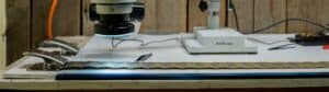 A digital microscope/camera takes close-up photos of a section of filter pleats spread out across a lab table.