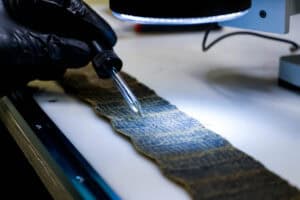 A lab technician drops acid on filter pleats, looking for a chemical reaction to identify the type of metal present.
