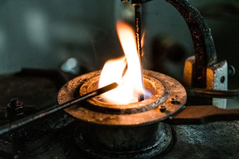 A picture of oil while the flashpoint test is being conducted. The oil is heated in a brass cup over a Bunsen burner, with a single flame placed above the oil as it's heated. When the vapors ignite, the lab technicians record the flashpoint temperature. We use this test to determine the quantity of fuel and other solvents present in the oil.
