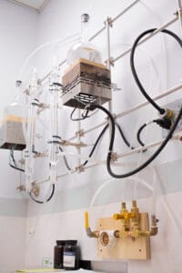 A photo of test tubes and beakers installed on the wall in our laboratory. This is where we distill our own water to ensure purity for use in the lab.