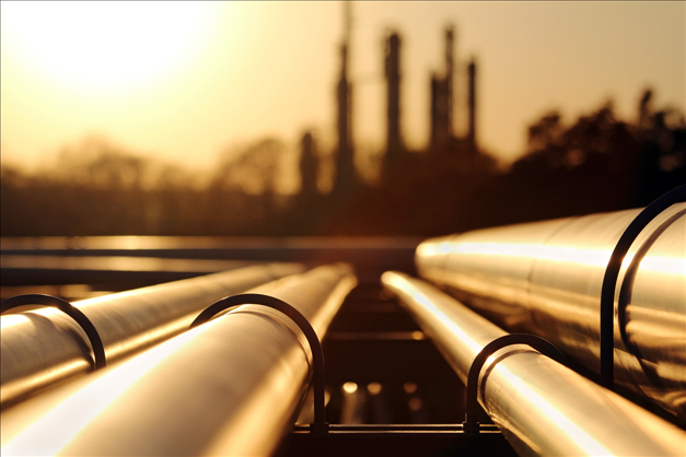 image of pipelines on the ground looking toward factory smokestacks