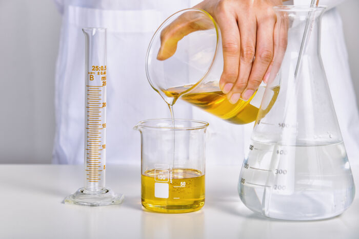Hand pouring oil into a glass container
