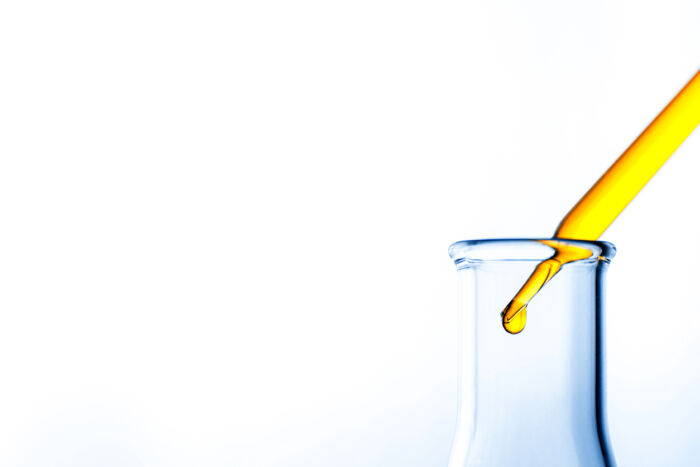 Dropper putting oil into a glass beaker