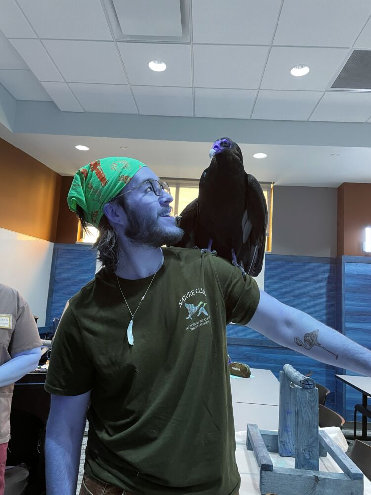Sam looking at a raptor sitting on his shoulder
